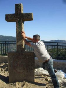 Una persona finge tumbar una cruz de madera de una tumba